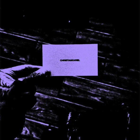 A hand holding a business card that reads CHRISTIANXARIEL, in purple and black