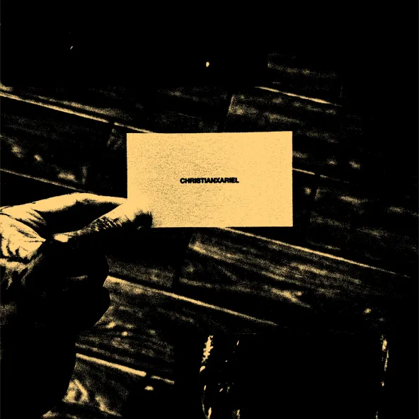 A hand holding a business card that reads CHRISTIANXARIEL, in gold and black